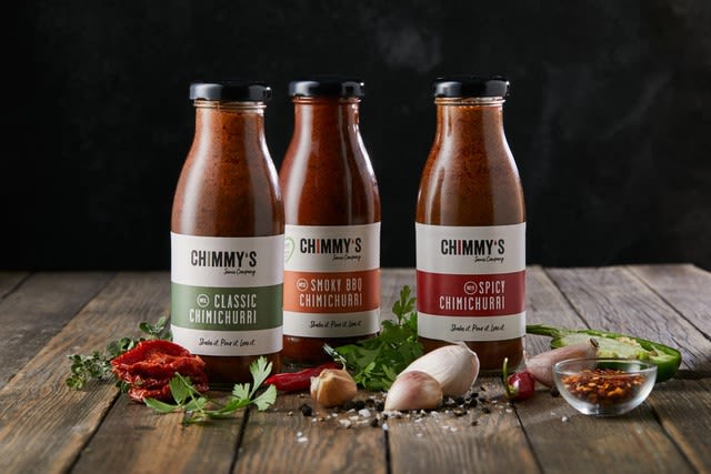 Three bottles of Chimmy's sauce on a wooden table