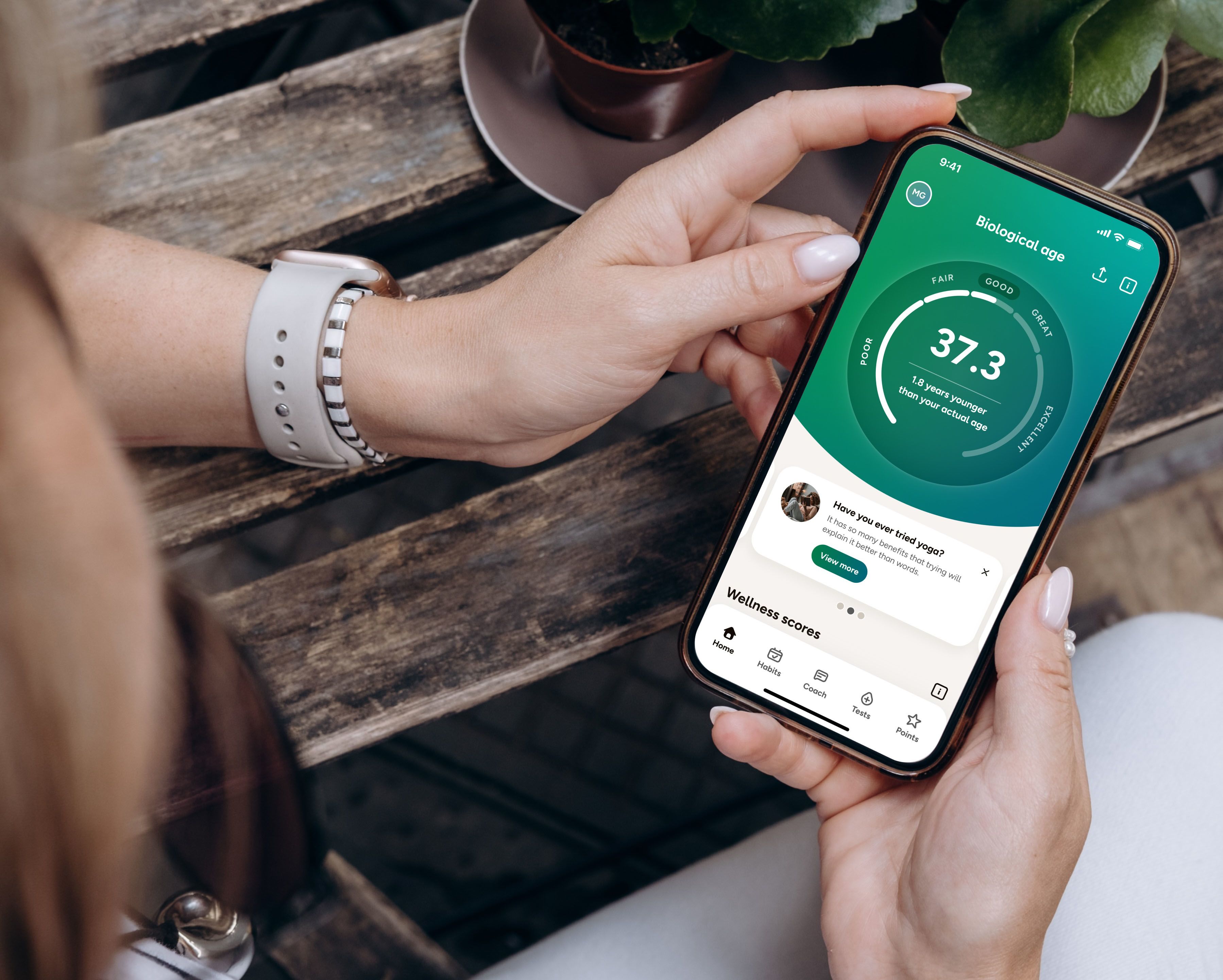 Hand holding a phone showing the H&B&Me app